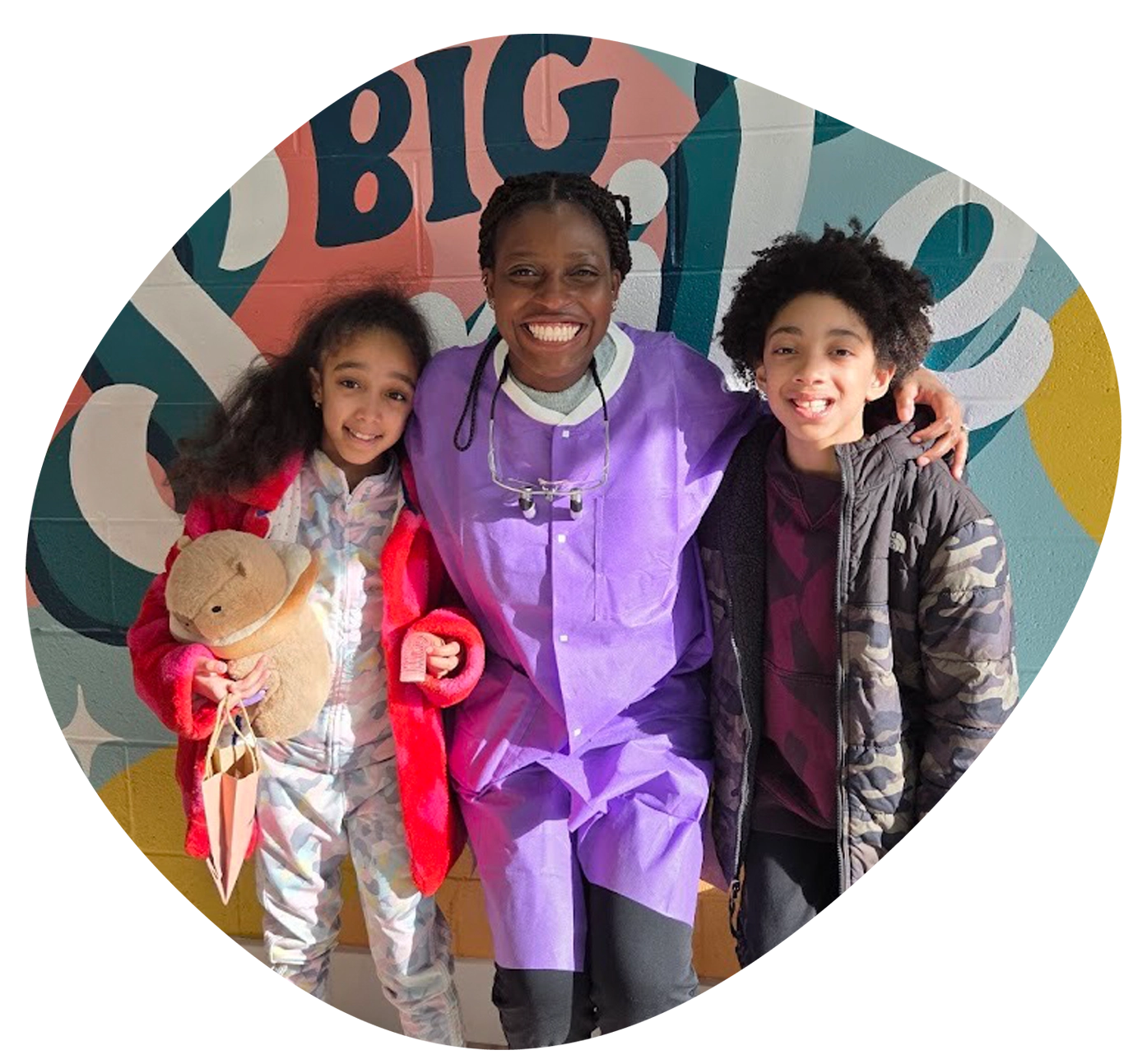 doctor ngobitak posing with children in front of mural wall